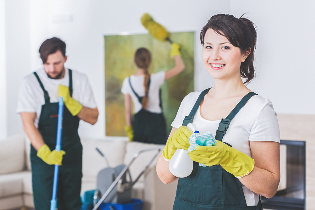 Smiling woman cleaner with her team cleaning residential home