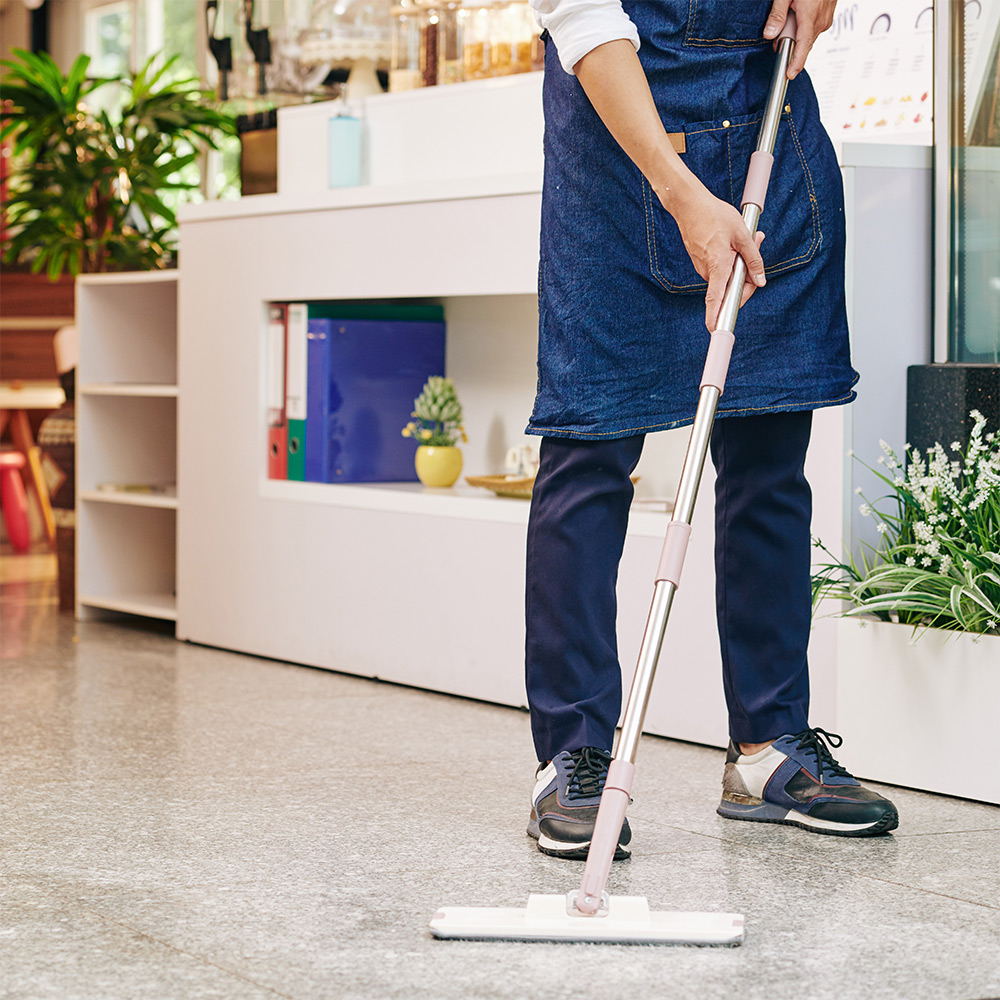 Cleaner mopping floor in retail shop